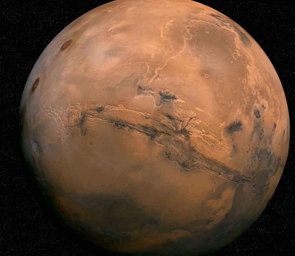Full disk image of Mars showing its red surface and dark volcanic regions